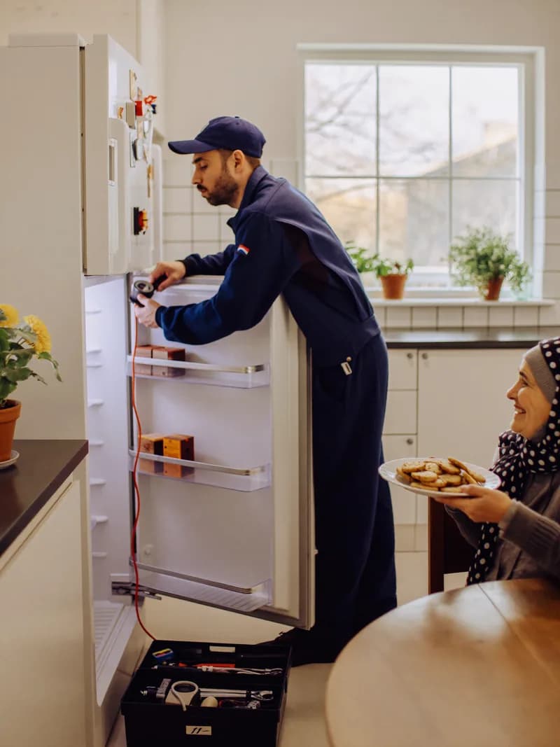Açık Ariston buzdolabının soğutma sistemini kontrol ederek onarım yapan servis teknisyeni