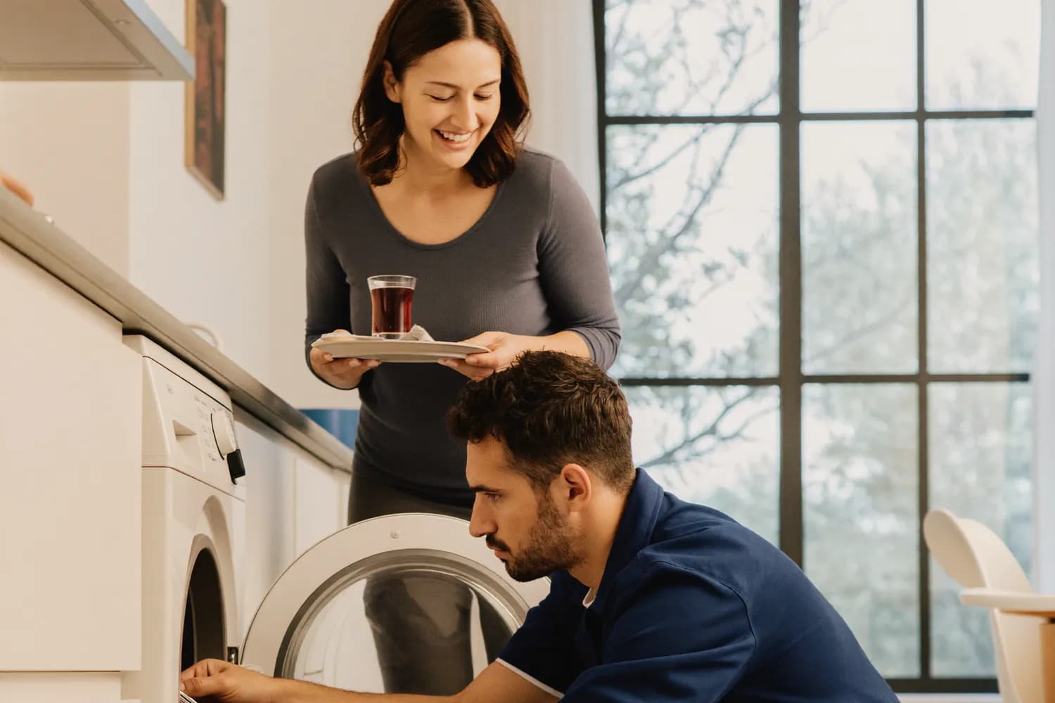 Ariston çamaşır makinesinin kapağını açıp pompa ve tambur arızasını gideren servis teknisyeni, müşteri çay ikram ediyor